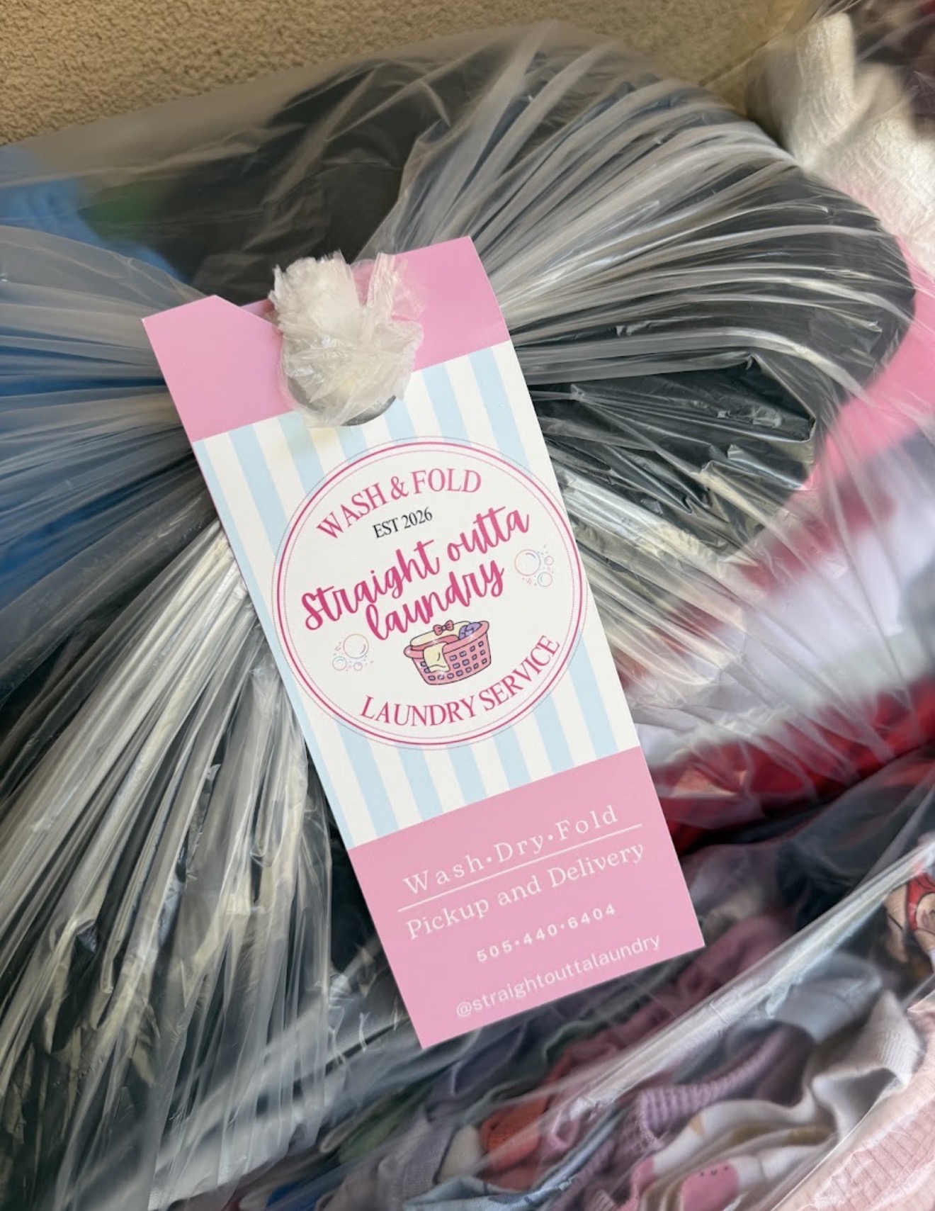 A finished Straight Outta Laundry order, bagged with a branded door-hanger tag